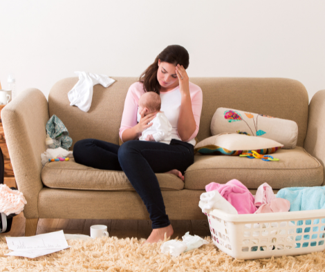 Woman sitting on couch feeling overwhelmed in a cluttered home