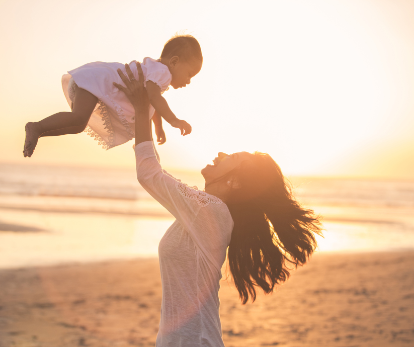 Parent lifting child at the beach symbolizing secure attachment and joy
