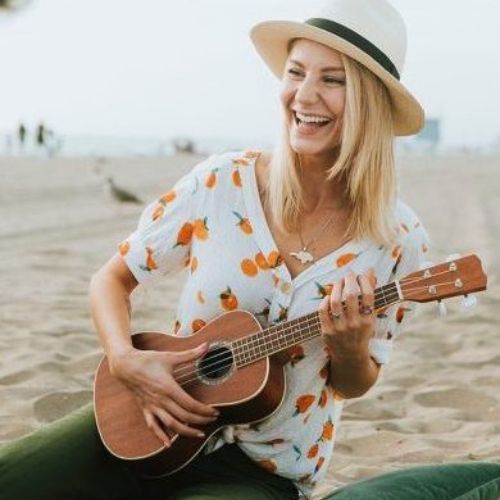 Woman playing ukulele on the beach expressing joy and creativity